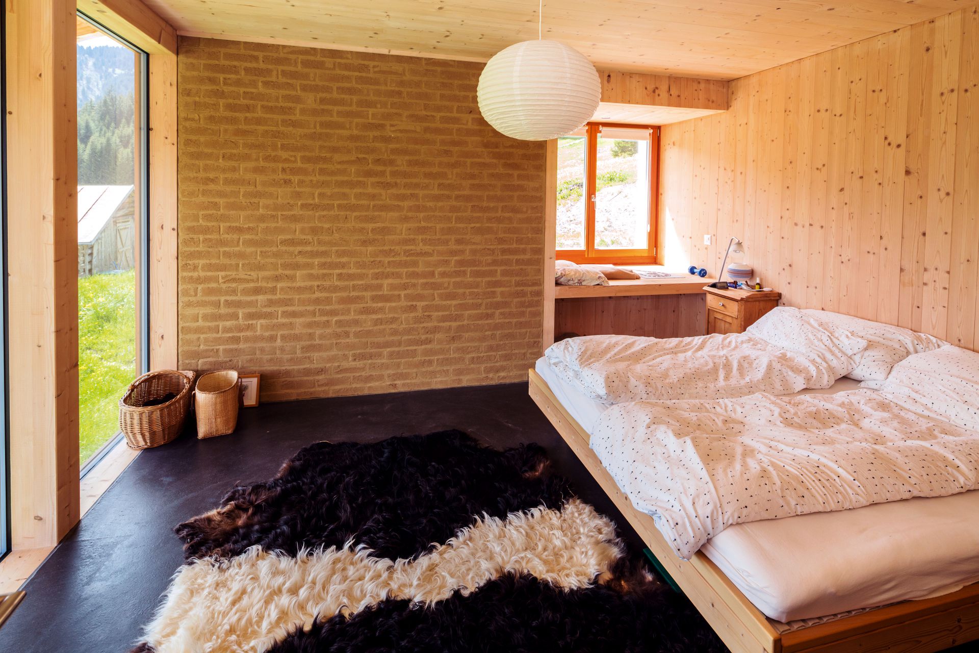 Beim Innenausbau (hier das Schlafzimmer) entschieden sich Sarah und Giusep Gliott für Holz und luftgetrocknete Lehmziegel.